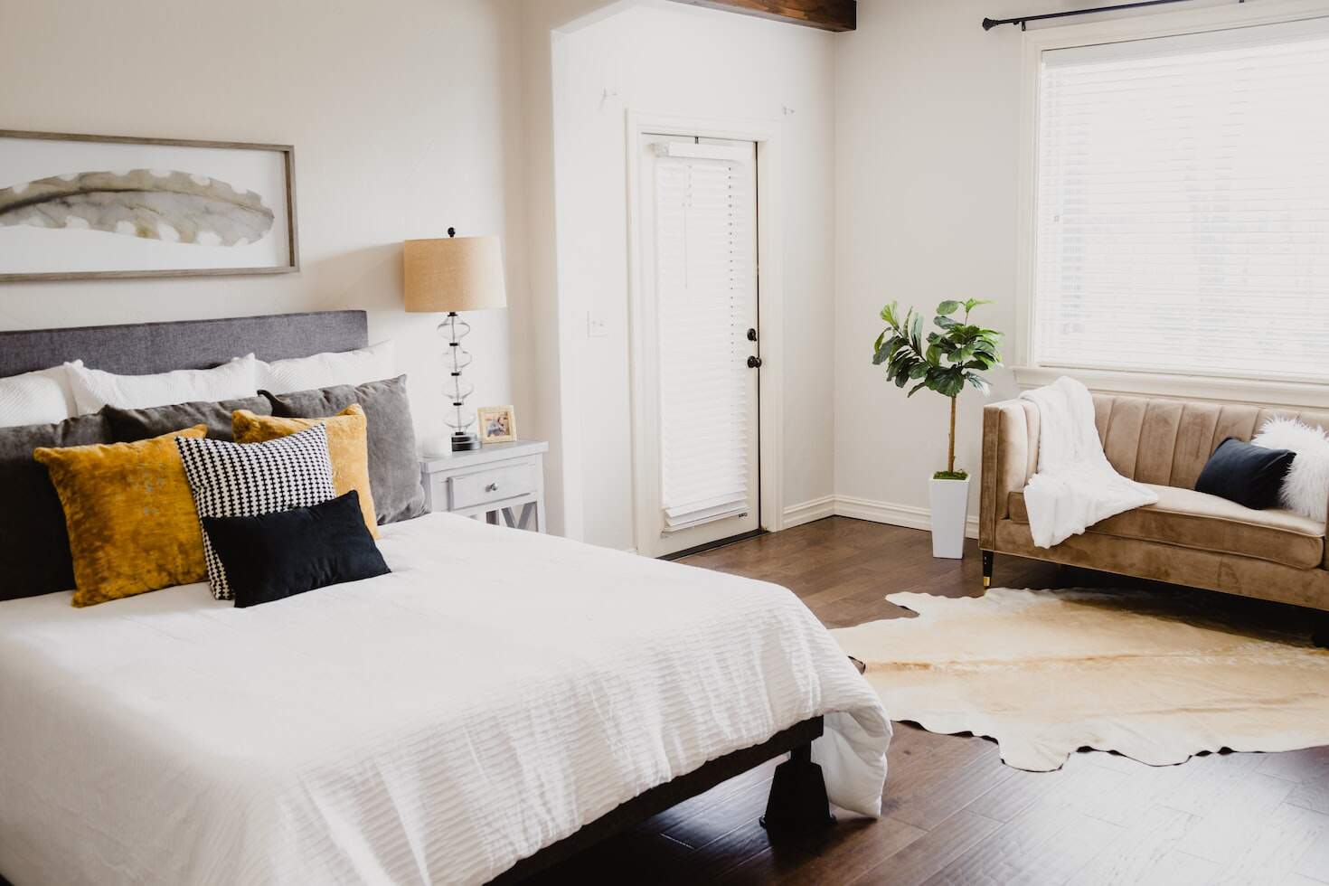 a white bedroom with burnt orange throw pillows and a white comforter